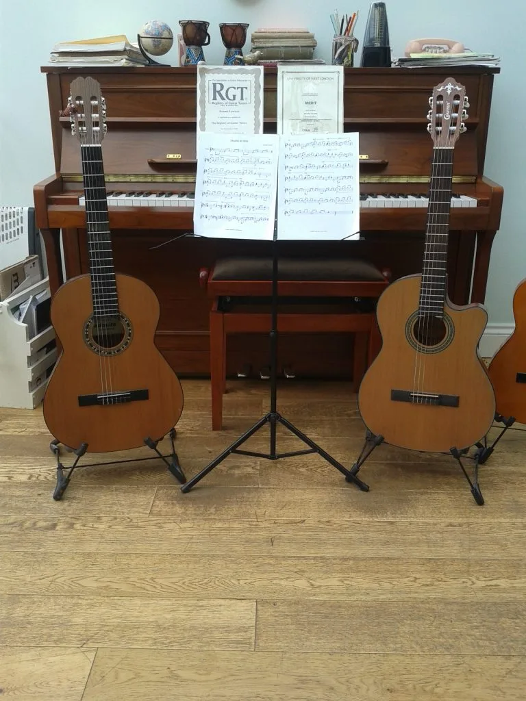 Two guitars by a piano with sheet music